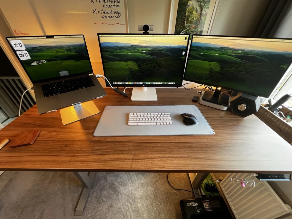 Top-down view of the Desktronic HomePro desk with a 16-inch MacBook Pro, 27-inch LG and 24-inch Philips monitor on the walnut-effect top