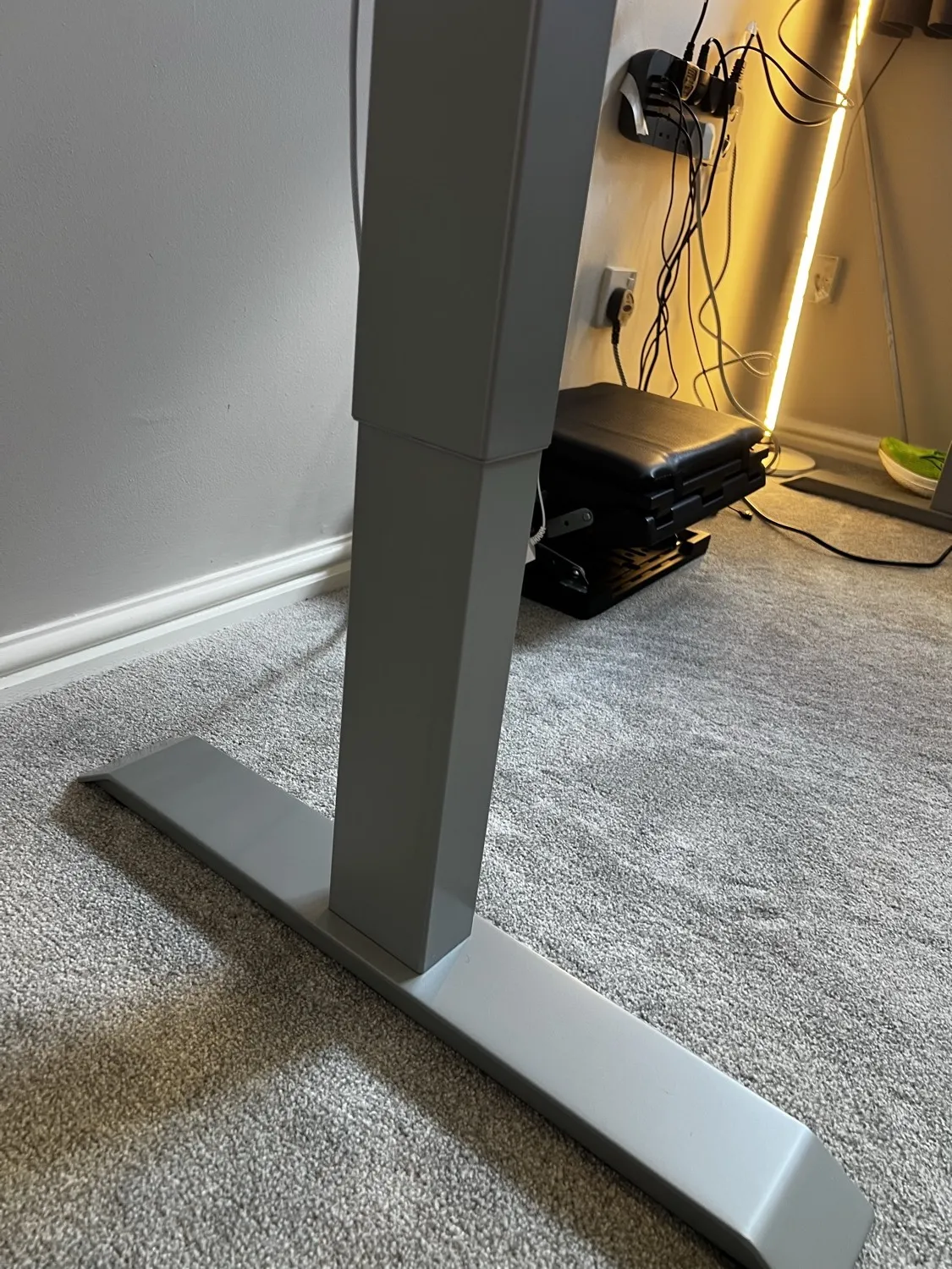 The grey three-stage leg and foot of the Desktronic HomePro frame on carpet