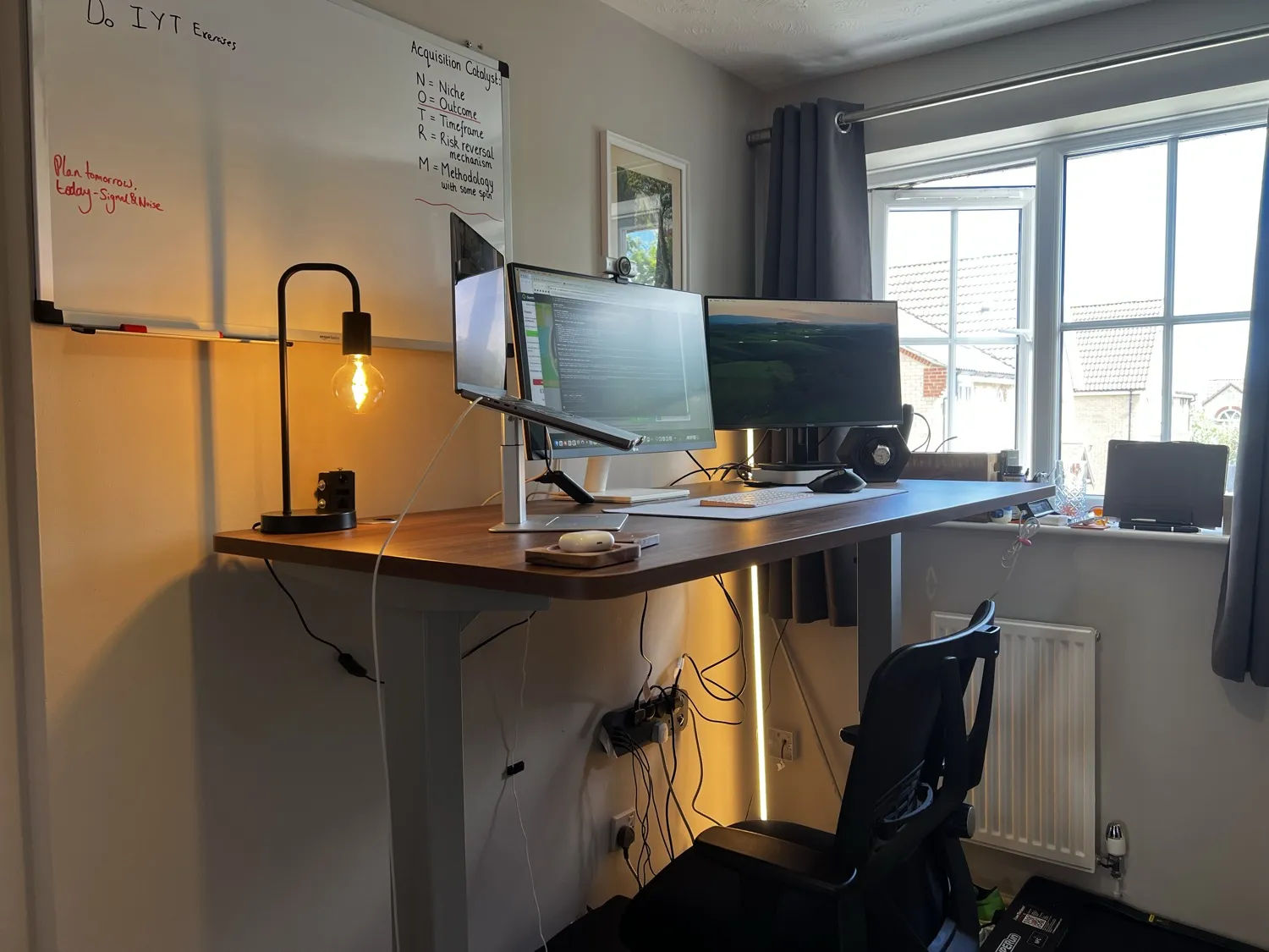 The Desktronic HomePro at full standing height with three screens, a lamp and a walking pad in a home office