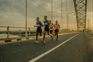 four athlete runners road running over a bridge together